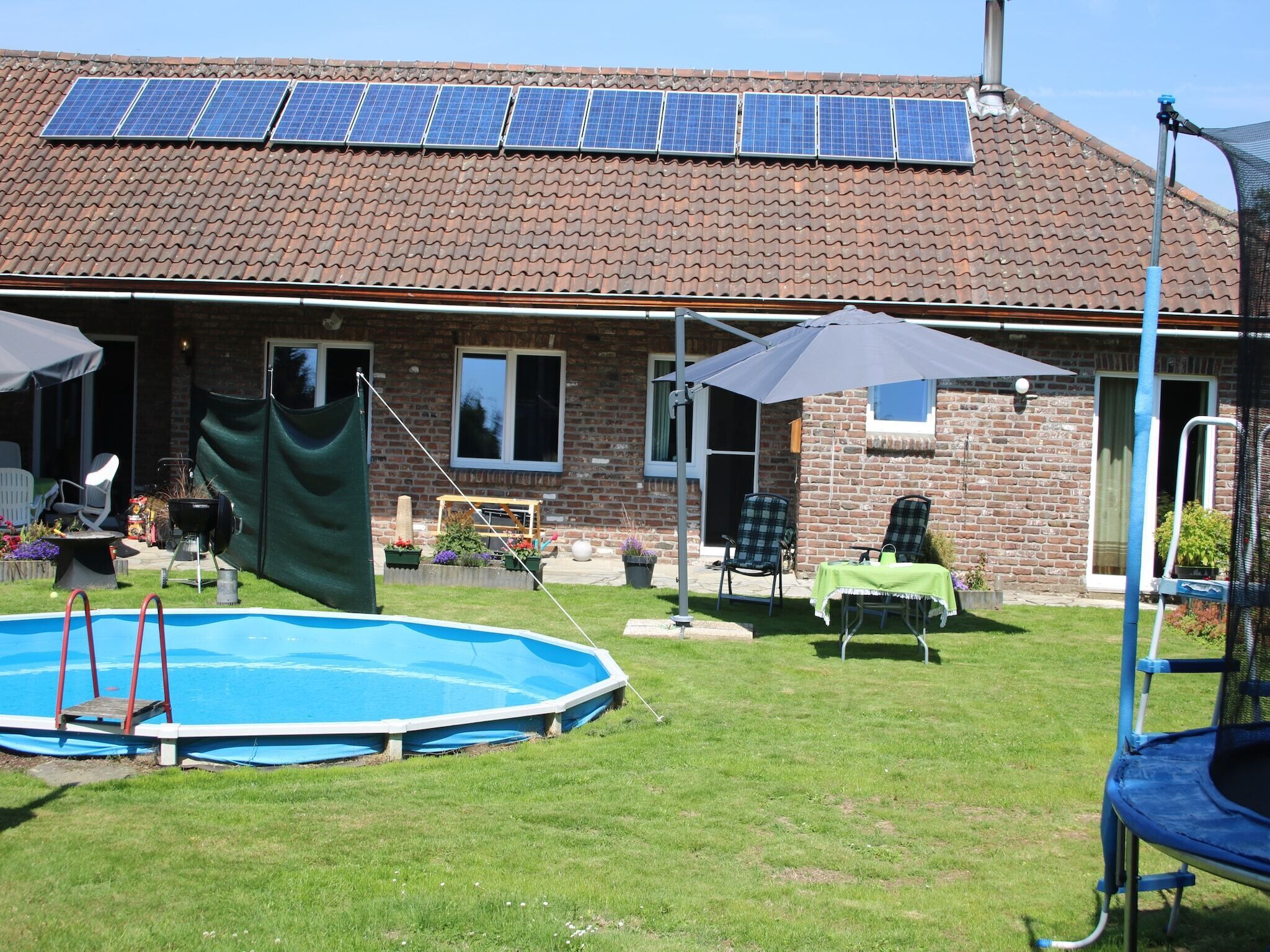 A backyard with a swimming pool, patio furniture, and solar panels on the roof.