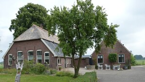 A traditional brick house with a thatched roof, a paved driveway, and a well-maintained lawn. - Holiday Home in Holten near Lake IJssel (Holten)