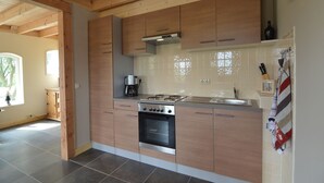 A modern kitchen with wooden cabinets, a stainless steel stove, and a tiled backsplash. - Holiday Home in Holten near Lake IJssel (Holten)