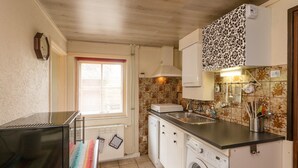 A compact kitchen with a built-in washing machine, a sink, and a stove.