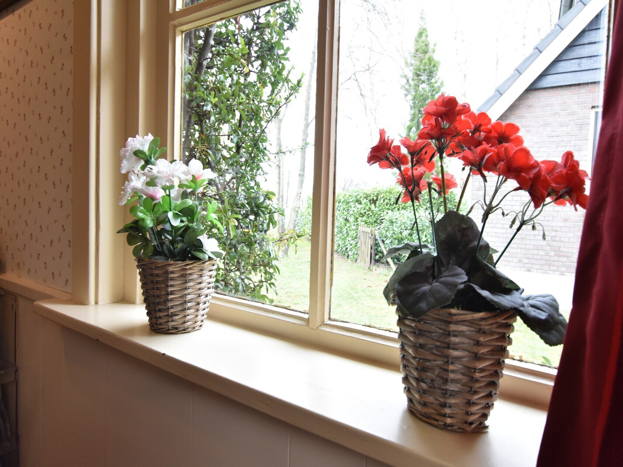 Two wicker baskets with flowers on a window sill.