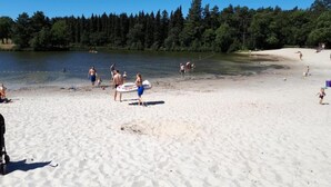 A sandy beach with people, a lake, and trees in the background. - Detached Home in Netherlands with Garden (Dalfsen)