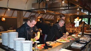 A buffet setup with multiple serving stations, plates, and a wine rack. - Tranquil Forest Retreat (Dalfsen)