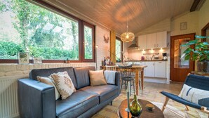 A cozy living room with a leather sofa, a dining table with chairs, and a kitchen in the background. - Holiday Home in Zorgvlied near Drents (Zorgvlied)