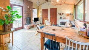 A cozy living room with a fireplace, wooden furniture, and a large window. - Holiday Home in Zorgvlied near Drents (Zorgvlied)