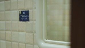 A bathroom with a white sink, a mirror, and a tiled wall.