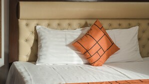 A neatly made bed with a headboard, two pillows, and a blanket.