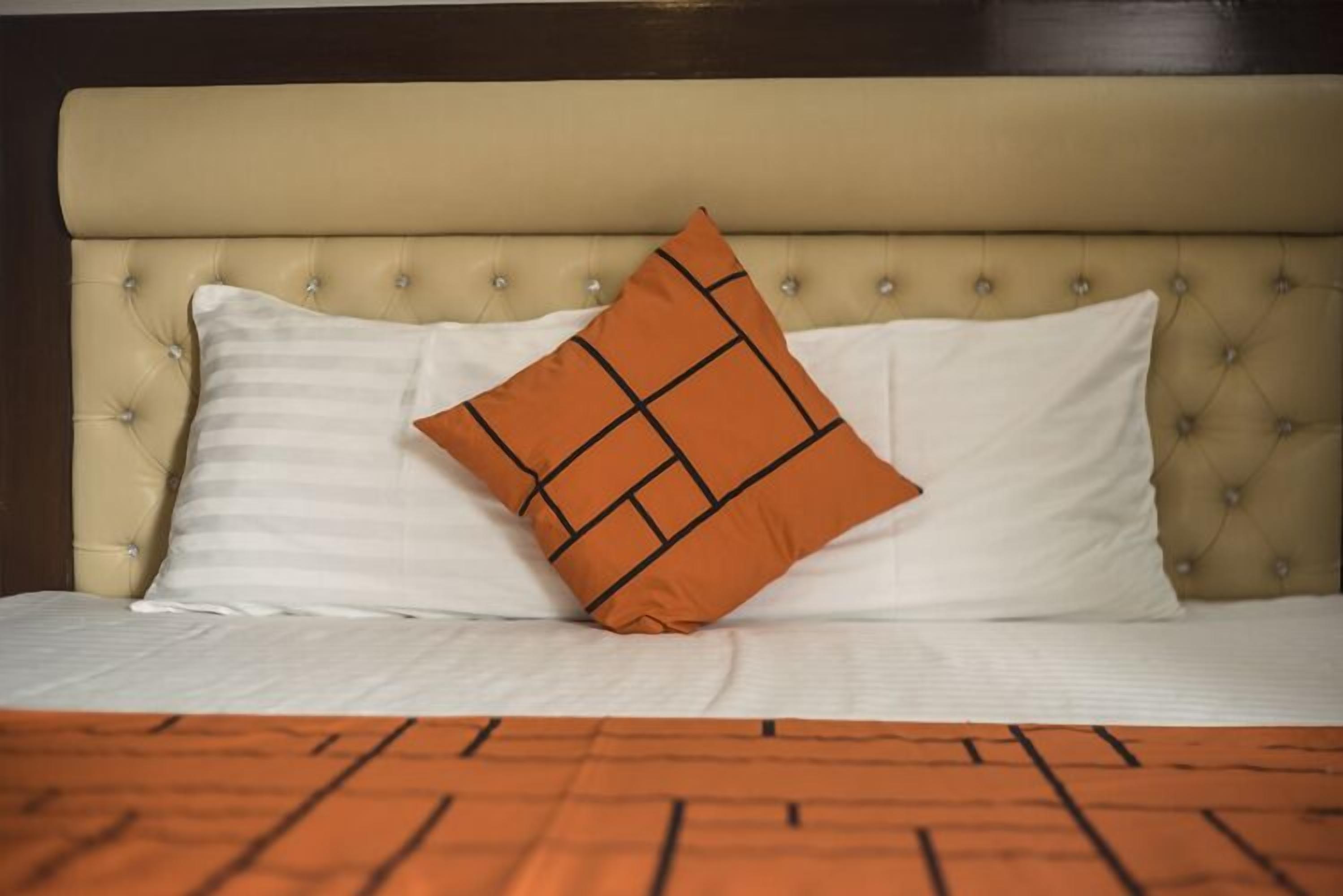 A bed with a tufted headboard, two pillows, and a patterned bedspread.