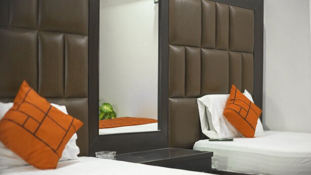 A hotel room with a large bed, a bedside table, and a mirror.