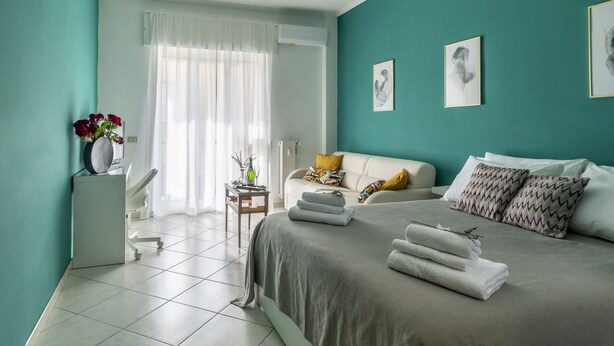 A modern bedroom with a bed, a bedside table, a chair, and a window with curtains. - 2 bedroom apartment in naples (Napoli)