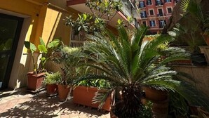 A courtyard with potted plants, a tiled floor, and a building with balconies. - 2 bedroom apartment in naples (Napoli)