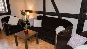 A room with a dark brown sofa, two armchairs, a wooden coffee table, and a potted plant.