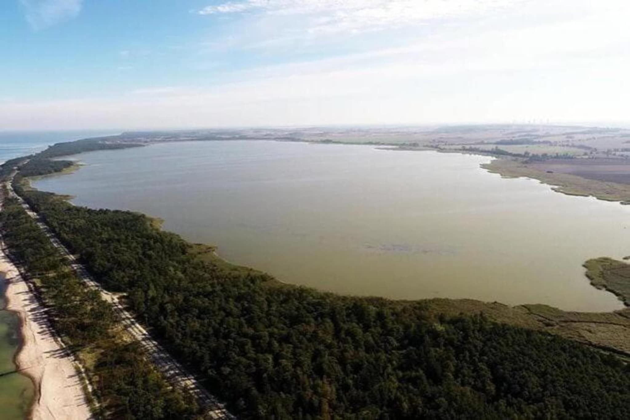 Une vaste étendue d’eau entourée d’une forêt dense et bordée d’une longue et étroite bande de terre.