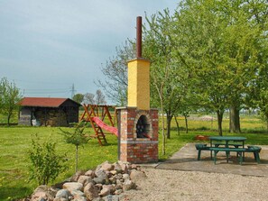 A brick oven structure with a chimney, a playground with a slide, and a picnic table in a grassy area. - Relaxing Seaside Getaway (Darłowo)