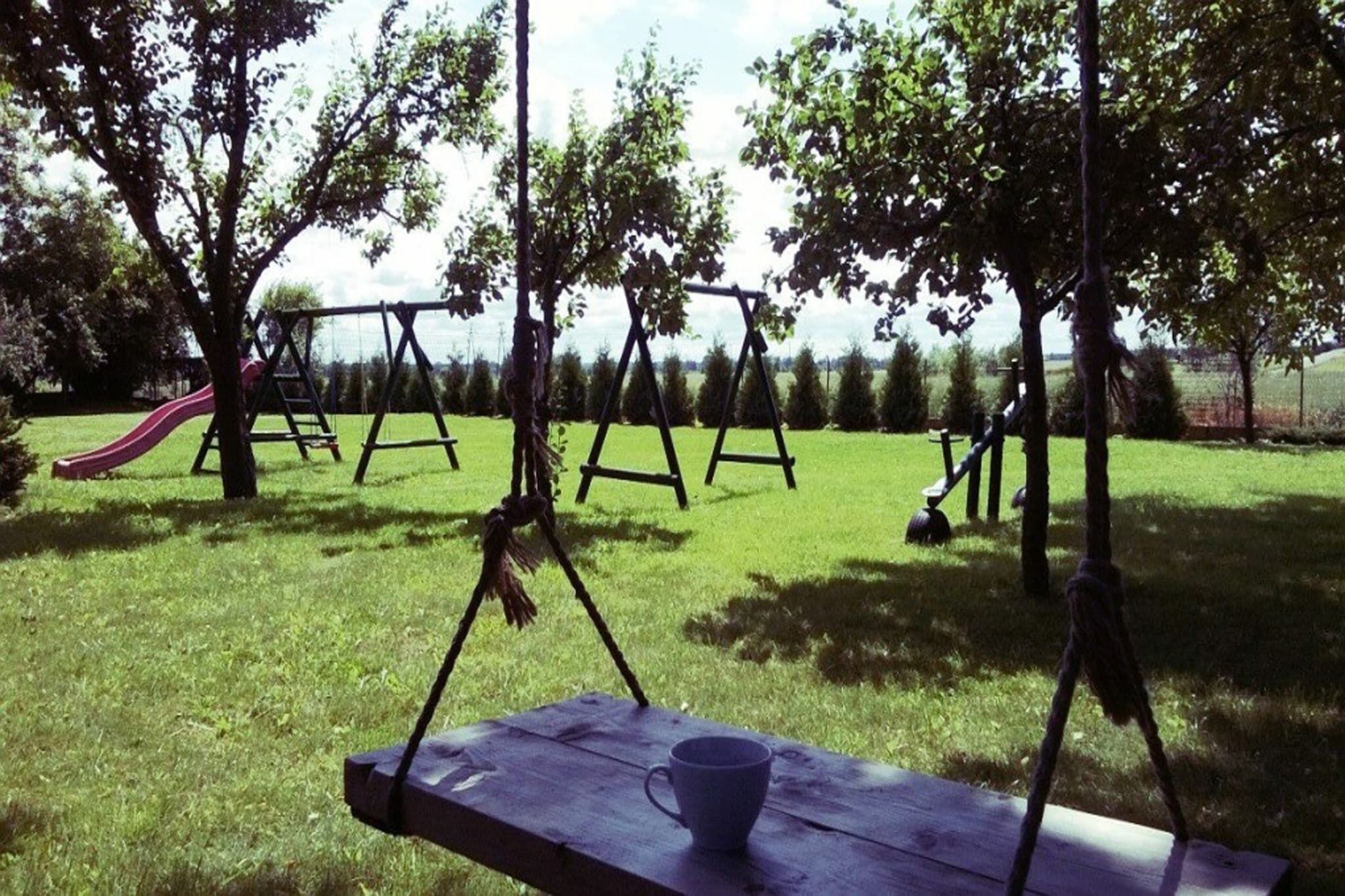A picnic table with a cup, a swing set, and a slide in a grassy park area.