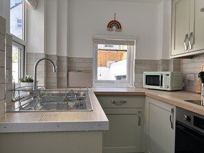 Cozinha moderna com pia embutida, micro-ondas e janela com vista para o exterior.