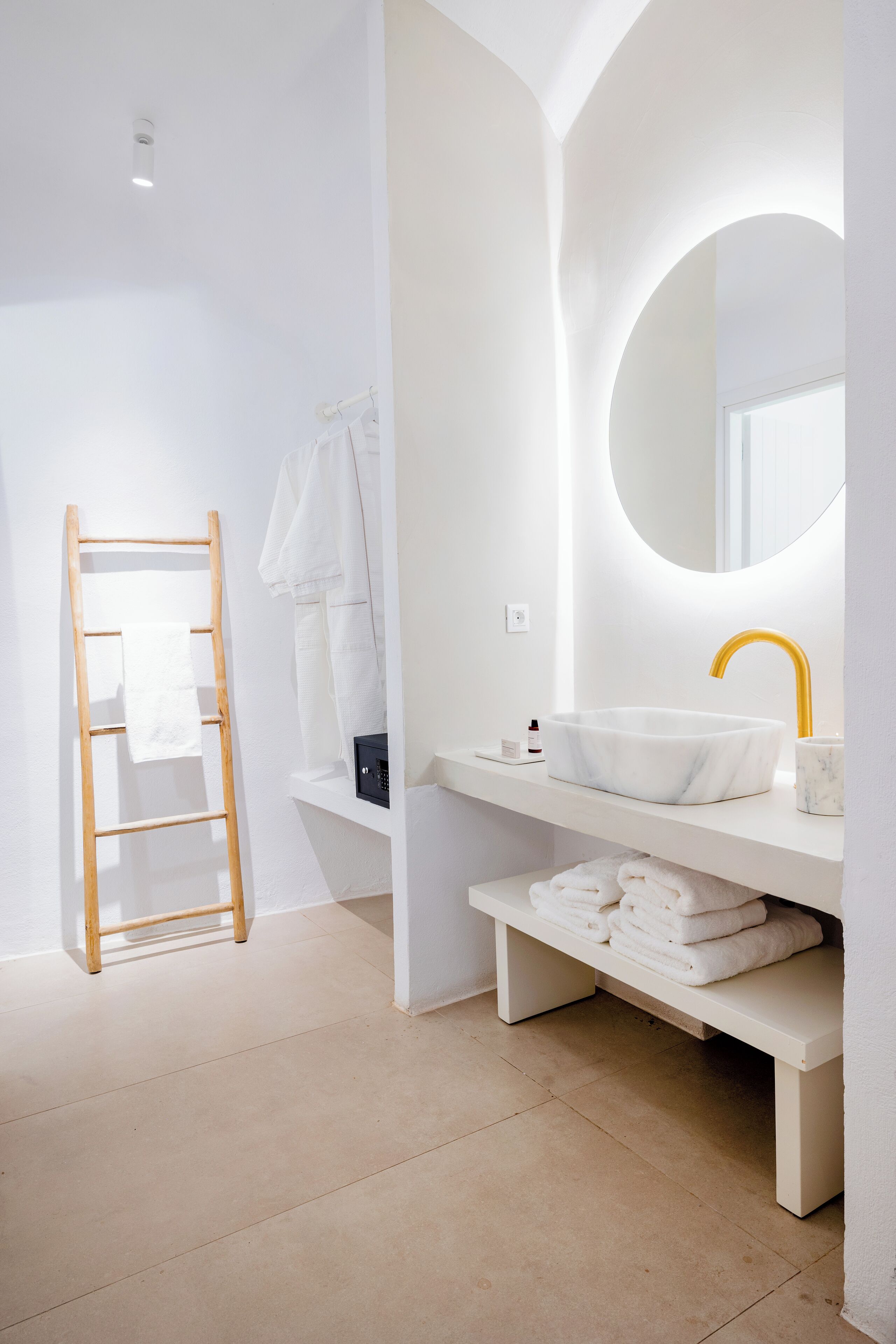 Une salle de bain moderne avec un meuble-lavabo blanc, un robinet doré et une échelle en bois.