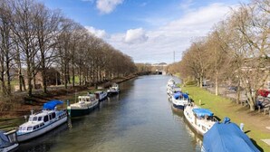 A canal with boats docked on both sides, surrounded by leafless trees and a clear sky. - Modern Dalhem Villa with Views (Dalhem)