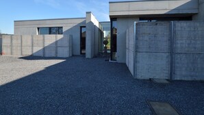 A modern building with a concrete exterior, a gravel driveway, and a clear sky. - Modern Dalhem Villa with Views (Dalhem)