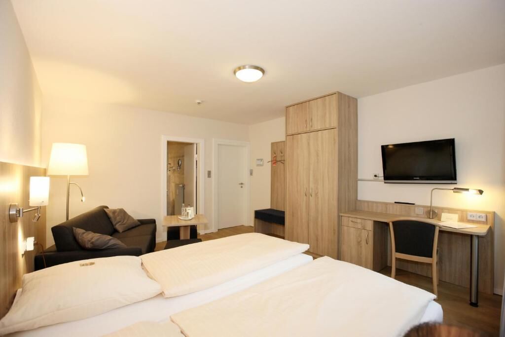 A hotel room with two beds, a desk, a television, and a wardrobe.