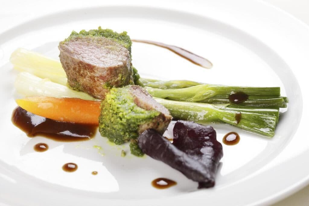 A plate with a piece of meat, broccoli, and vegetables.