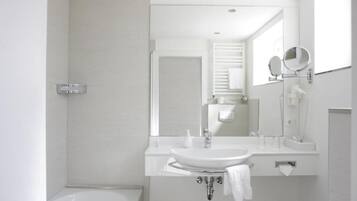 A modern bathroom with a white sink, mirror, and bathtub.