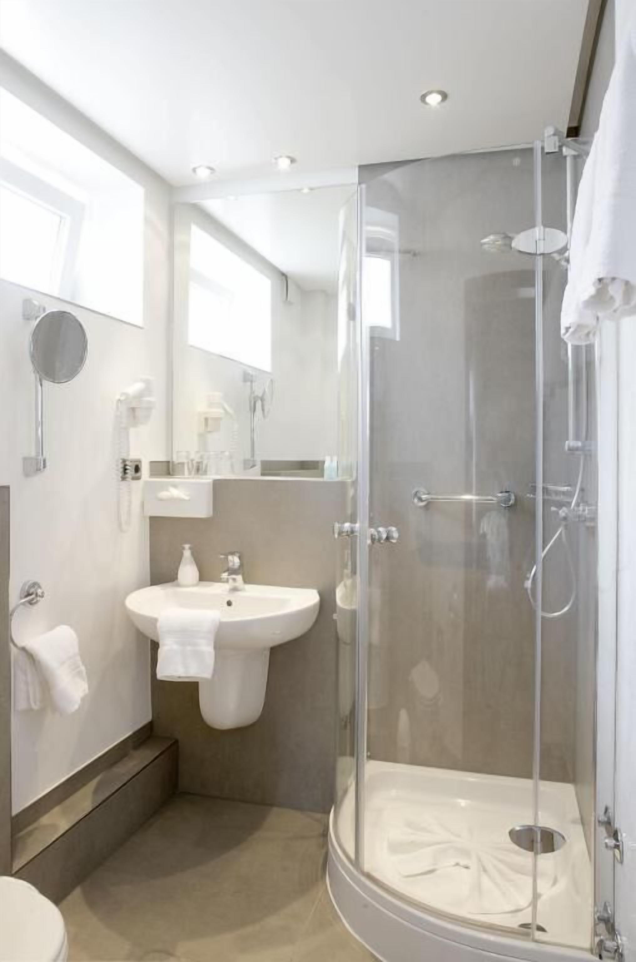 A modern bathroom with a glass-enclosed shower, a sink with a mirror, and a toilet.