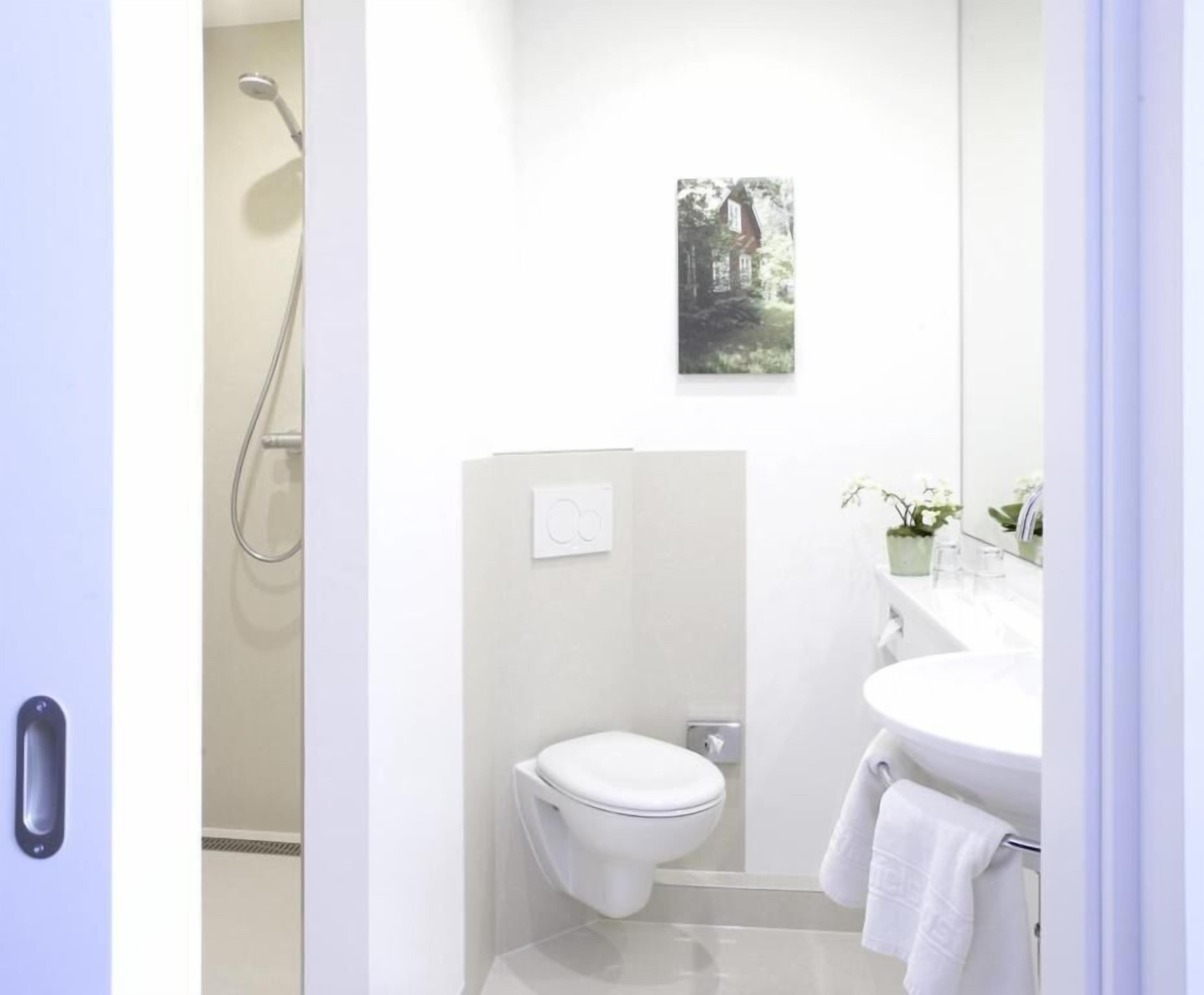 A modern bathroom with a toilet, shower, and sink.