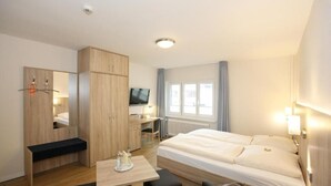 Une chambre d’hôtel équipée d’un lit, d’un bureau, d’une télévision et d’une armoire.