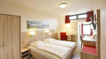A hotel room with two beds, a desk, a chair, a wardrobe, and a painting of a bridge.