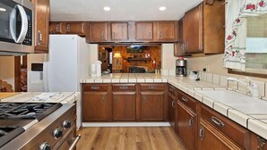 Una cocina con armarios de madera, microondas, estufa y refrigerador.