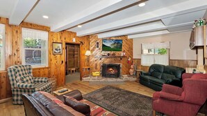 Una sala de estar acogedora con chimenea, paredes de madera y asientos cómodos.