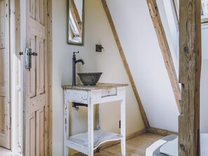 A rustic bathroom with a wooden door, a white sink with a basin, and a mirror on the wall. - Spacious authentic Polish farmhouse (Janowice Wielkie)