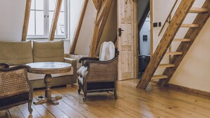Un espacio tipo loft con vigas de madera, un sofá, una silla y una pequeña mesa.