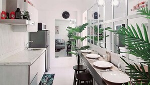 A modern kitchen with a central island, black bar stools, and a long dining table. - Azure Urban Resort Staycation-First ever large scale man made beach in the City. (Parañaque)
