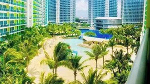 A resort with high-rise buildings, a pool, and palm trees. - Azure Urban Resort Staycation-First ever large scale man made beach in the City. (Parañaque)
