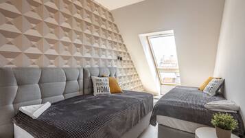 Une chambre moderne avec deux lits, un papier peint à motifs géométriques et une vue sur la ville grâce à une lucarne.