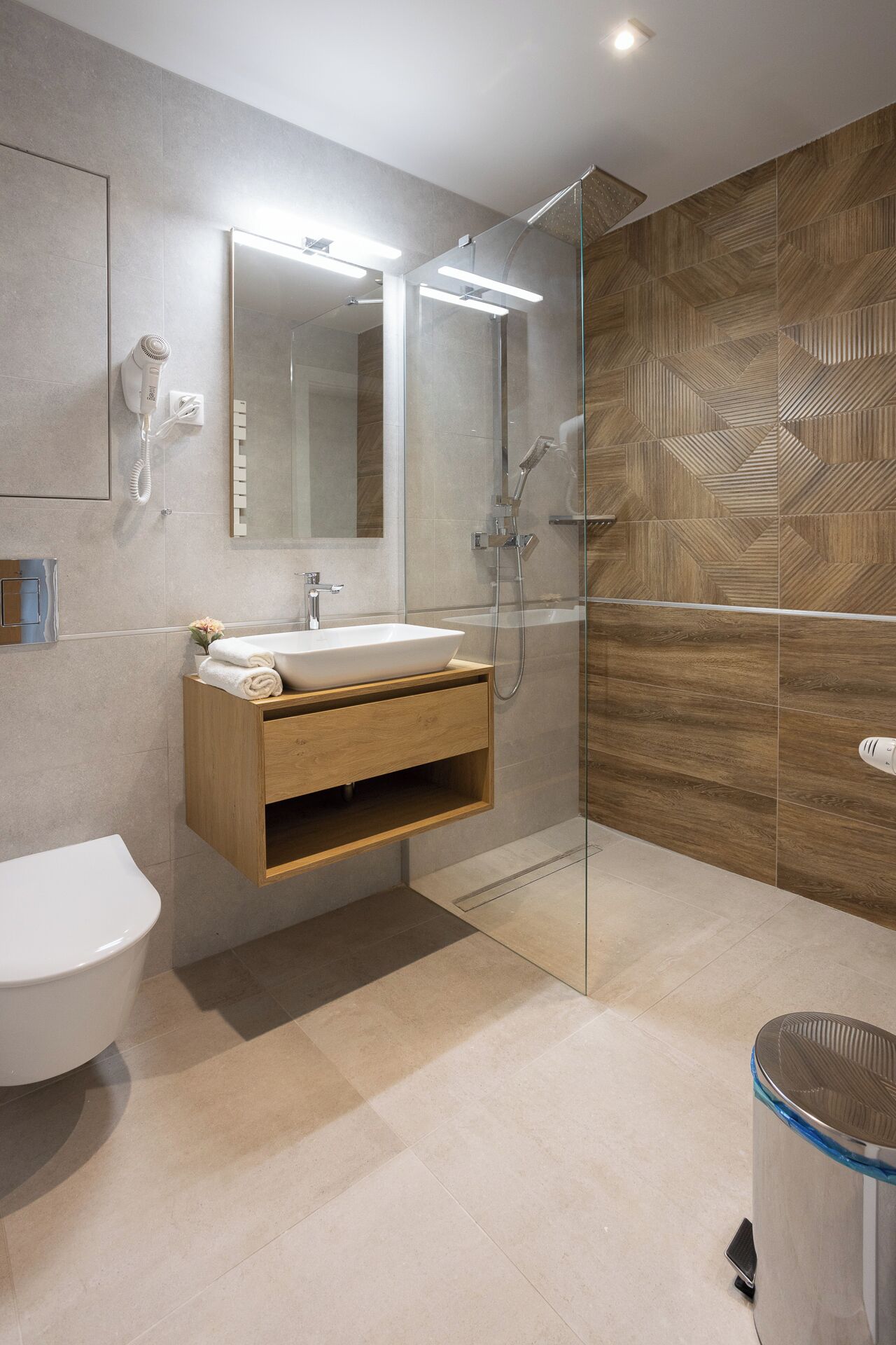 Une salle de bain moderne avec une douche à parois de verre, un meuble-lavabo en bois et un grand miroir.