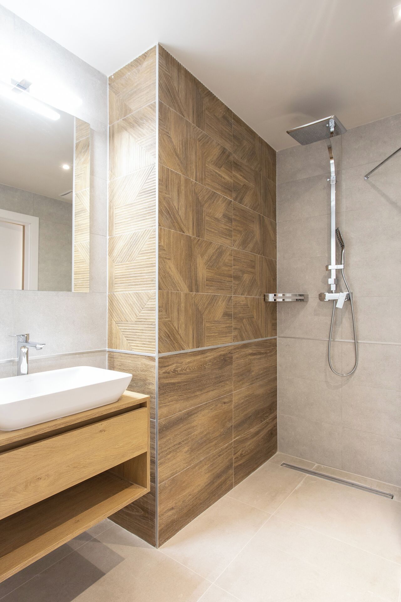 A modern bathroom with a wooden vanity, a large mirror, and a shower area.