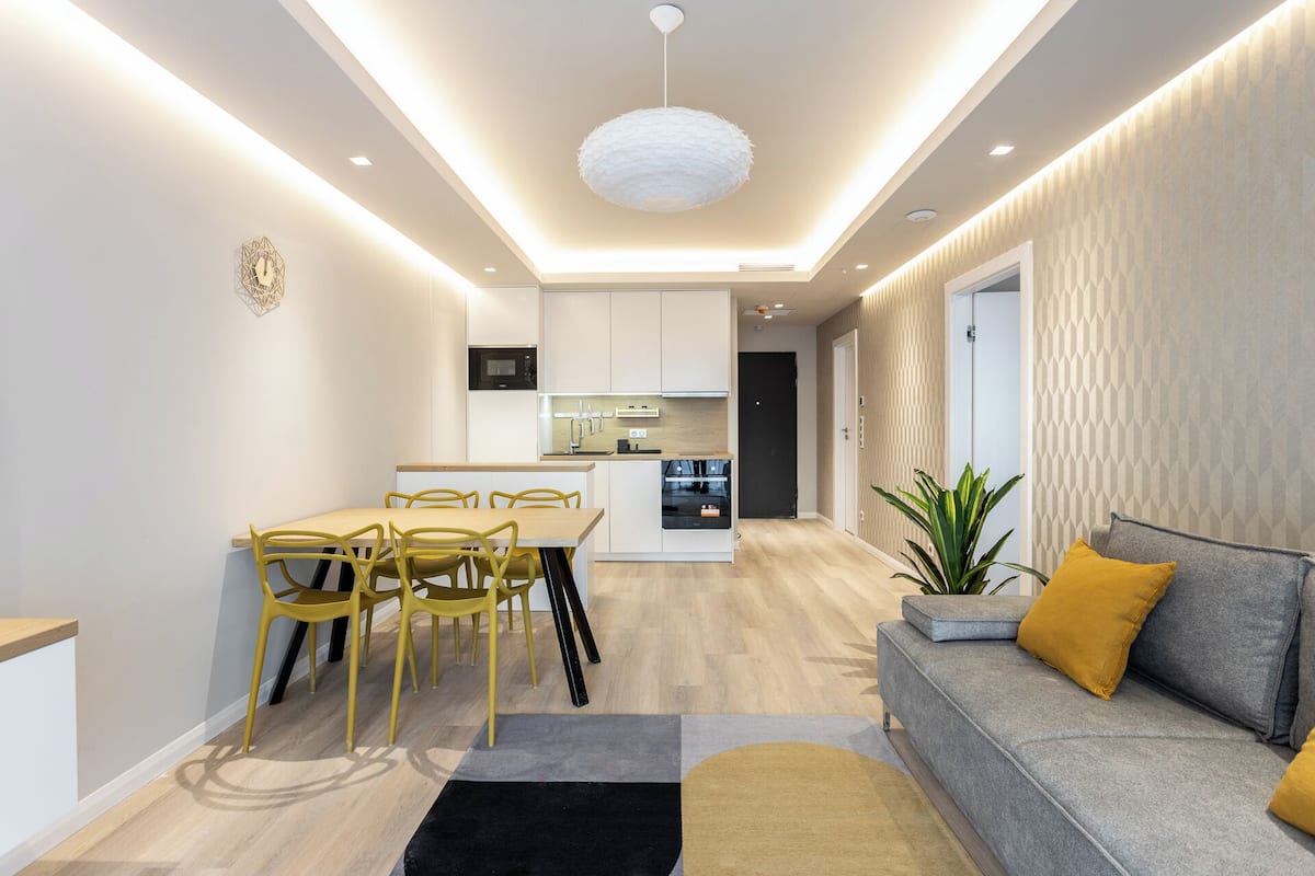 A modern living room with a grey sofa, yellow chairs, and a dining table.