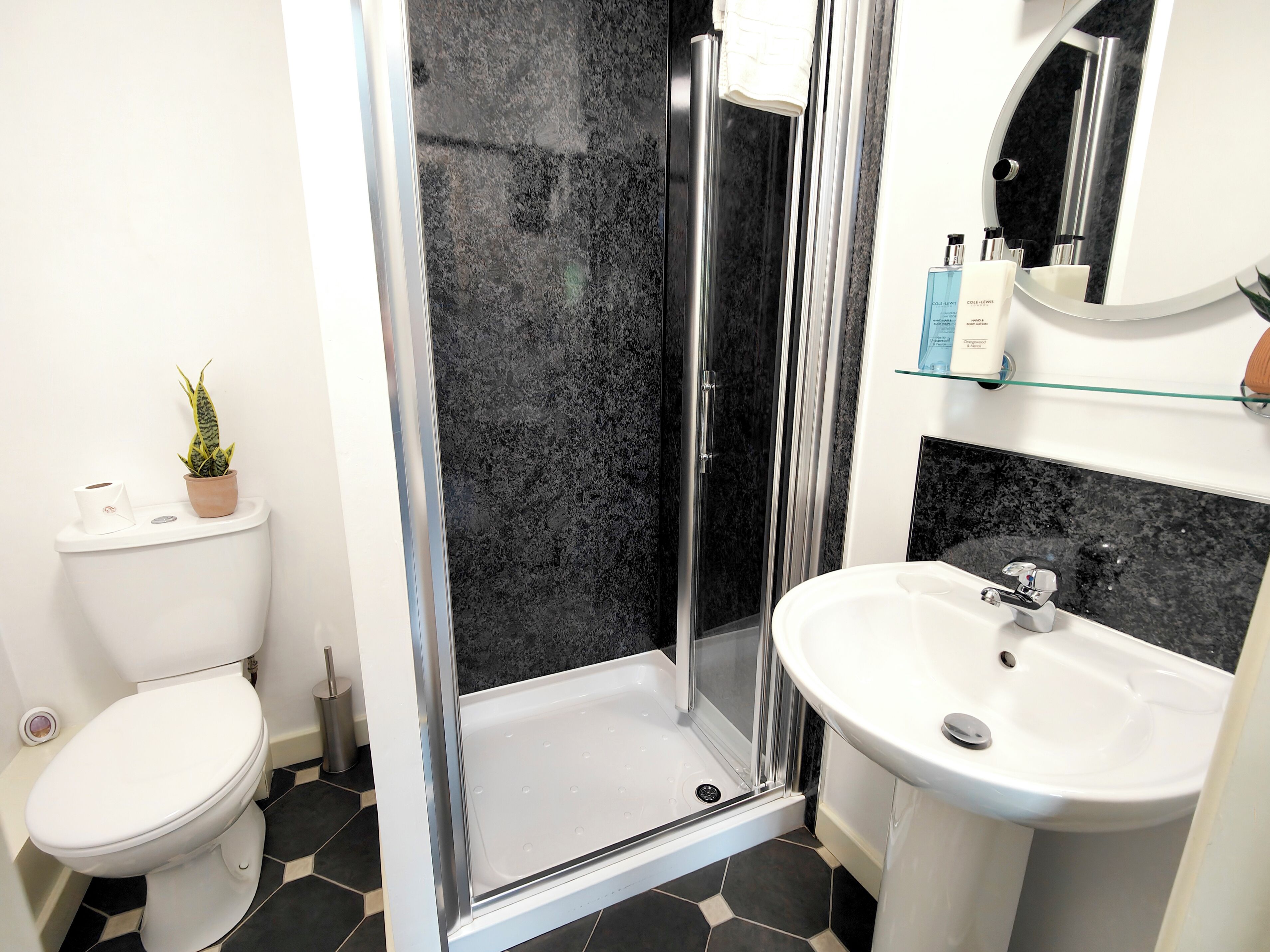 Een moderne badkamer met toilet, douchecabine en wastafel.