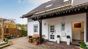 A house with a tiled roof, a white door, and a wooden bench outside. - Gemütliche Ferienwohnung am Waldrand (Eslohe)
