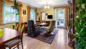A spacious living room with a wooden dining table, two sofas, a TV, and a chandelier. - Gemütliche Ferienwohnung am Waldrand (Eslohe)