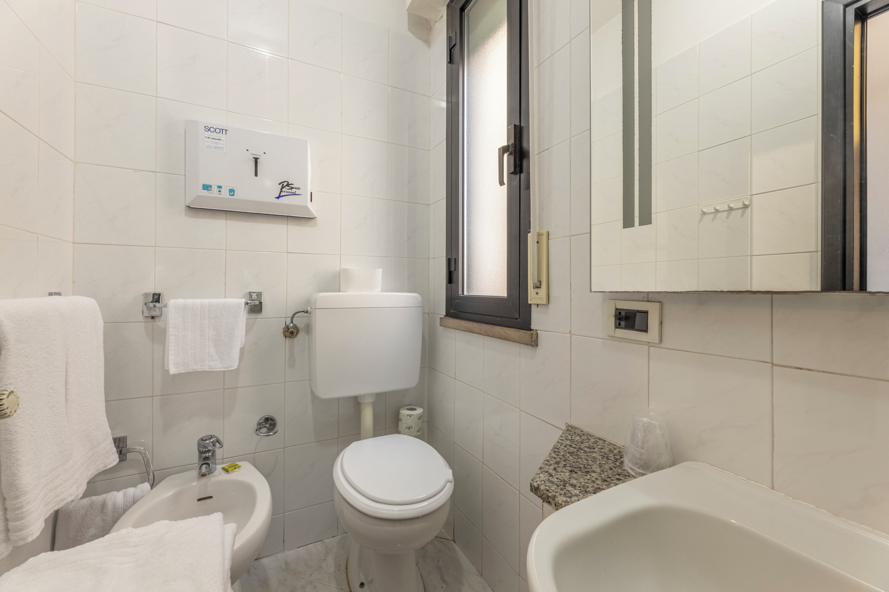 Baño con inodoro, bidé, lavamanos y bañera.
