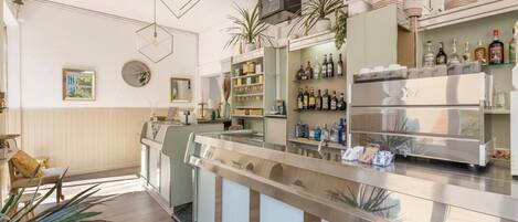 Uma área de bar moderna com balcão, prateleiras de garrafas e geladeira.