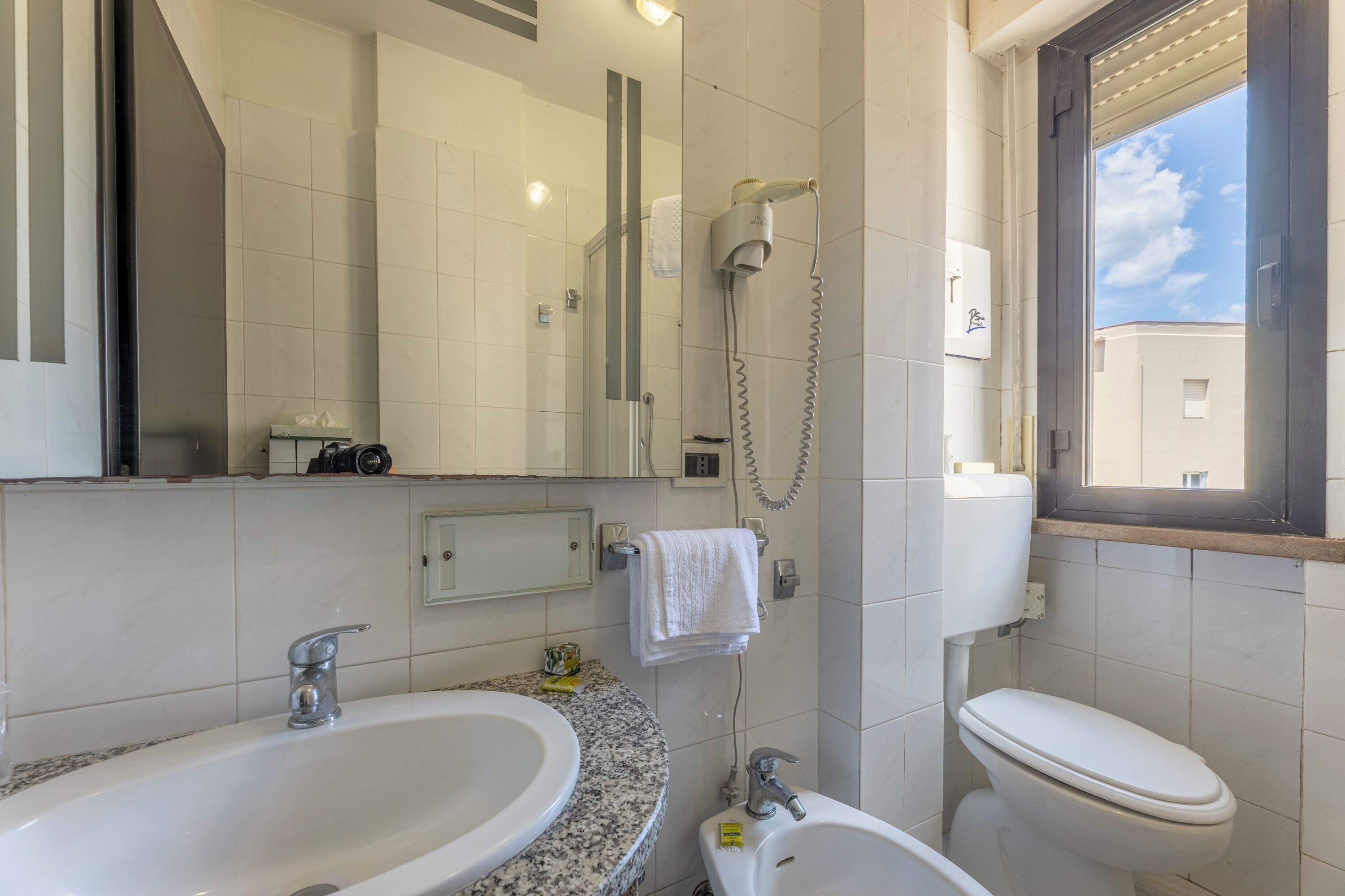 Un bagno con lavandino, specchio, asciugamano e water.