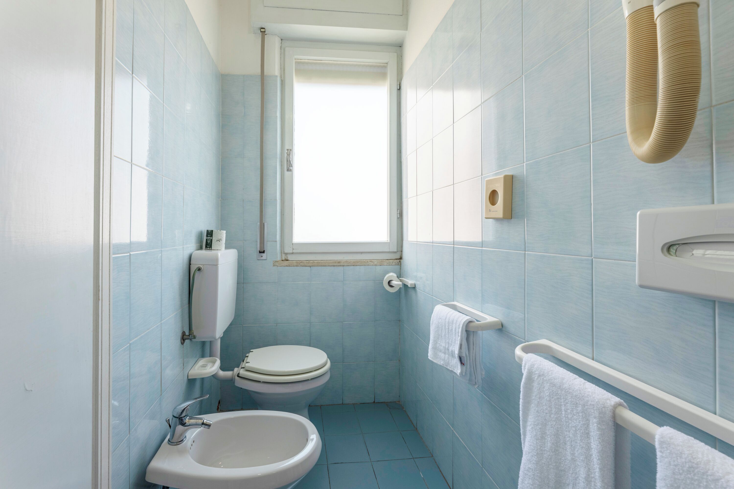 A small bathroom with a toilet, sink, and towel rack.