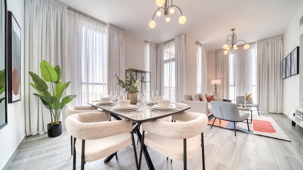 Un espace de salle à manger moderne avec une table ronde, des chaises et un lustre.