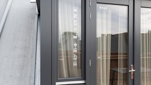 Een modern gebouw met een grijze gevel en een glazen deur met nummer 8142.