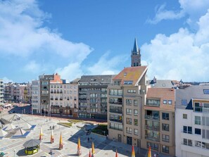 Un paysage urbain avec des bâtiments modernes, une tour imposante et une place ornée de drapeaux.